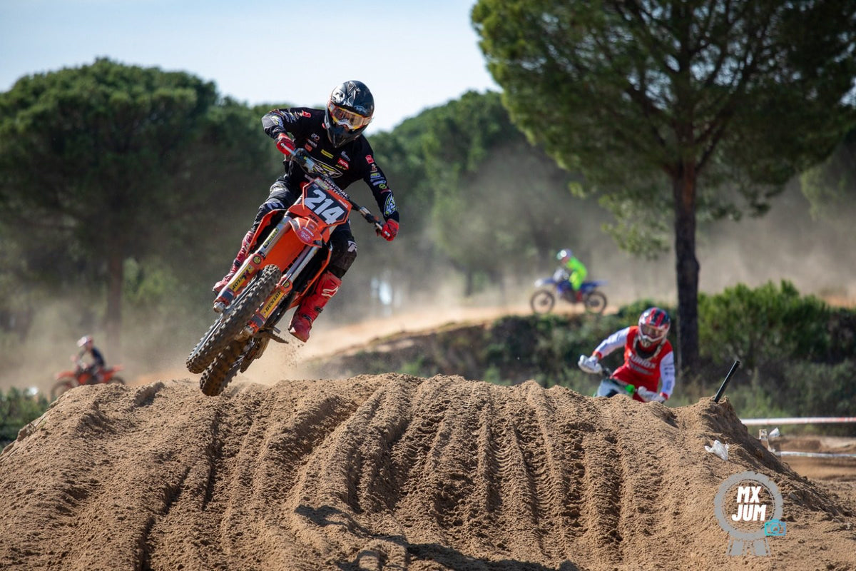 Piloto de motocross saltando sobre baches con polvo